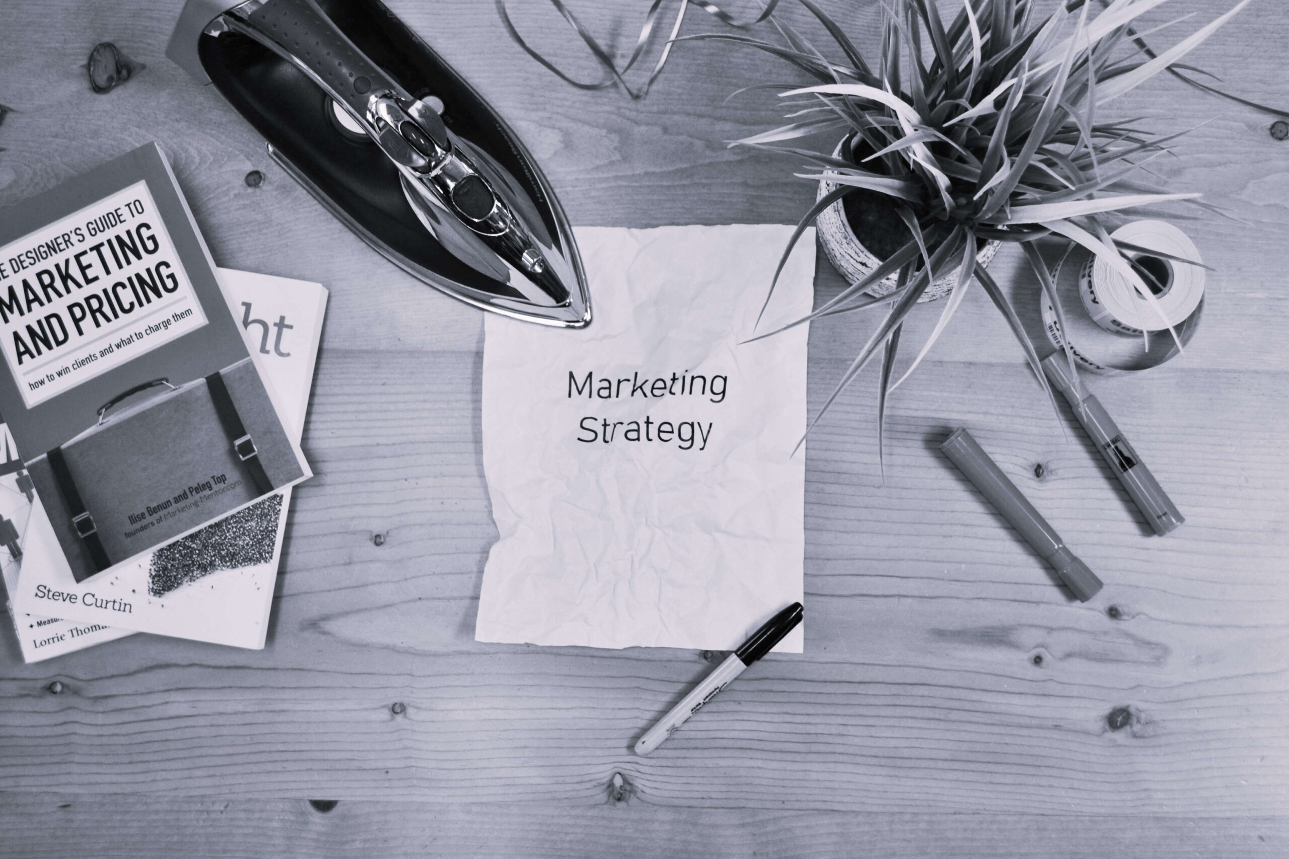 marketing strategy note around books and stationery on a wooden desk